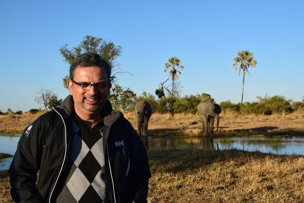 IB posing for picture on opposite bank of river from elephants